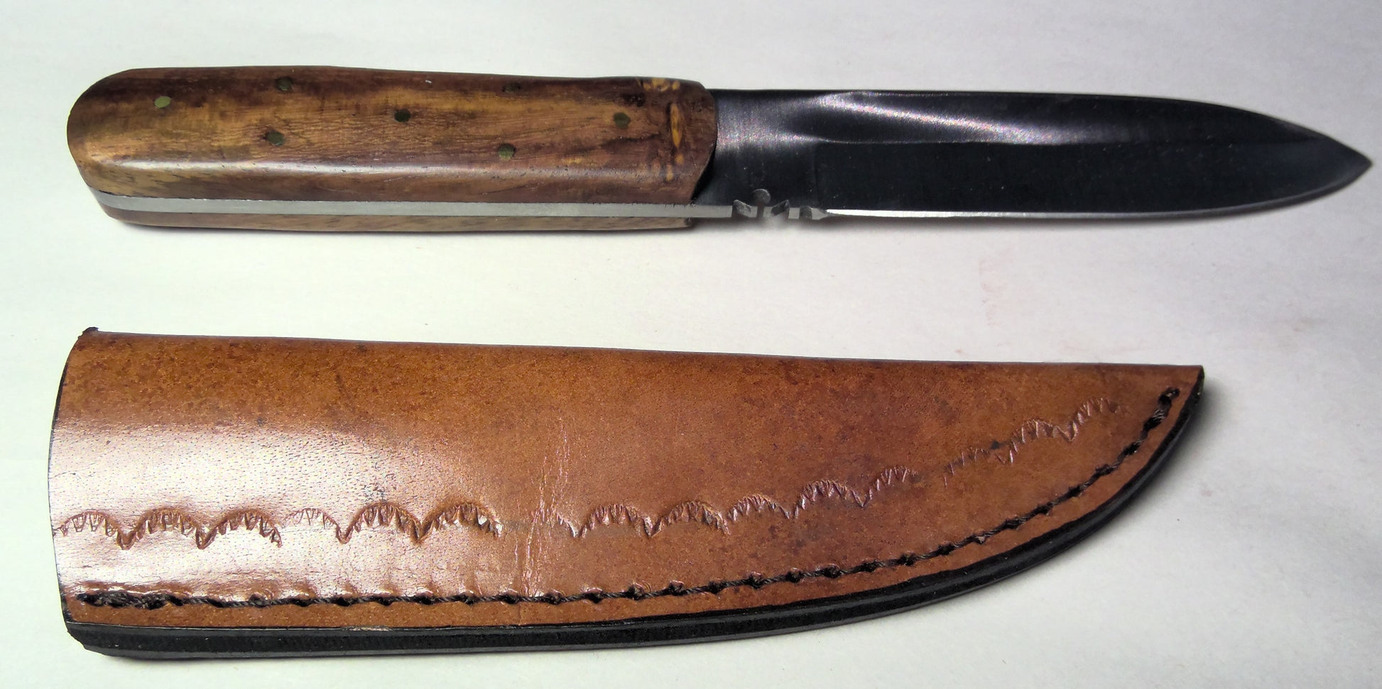 Knife with wooden handle and leather sheath on a white background