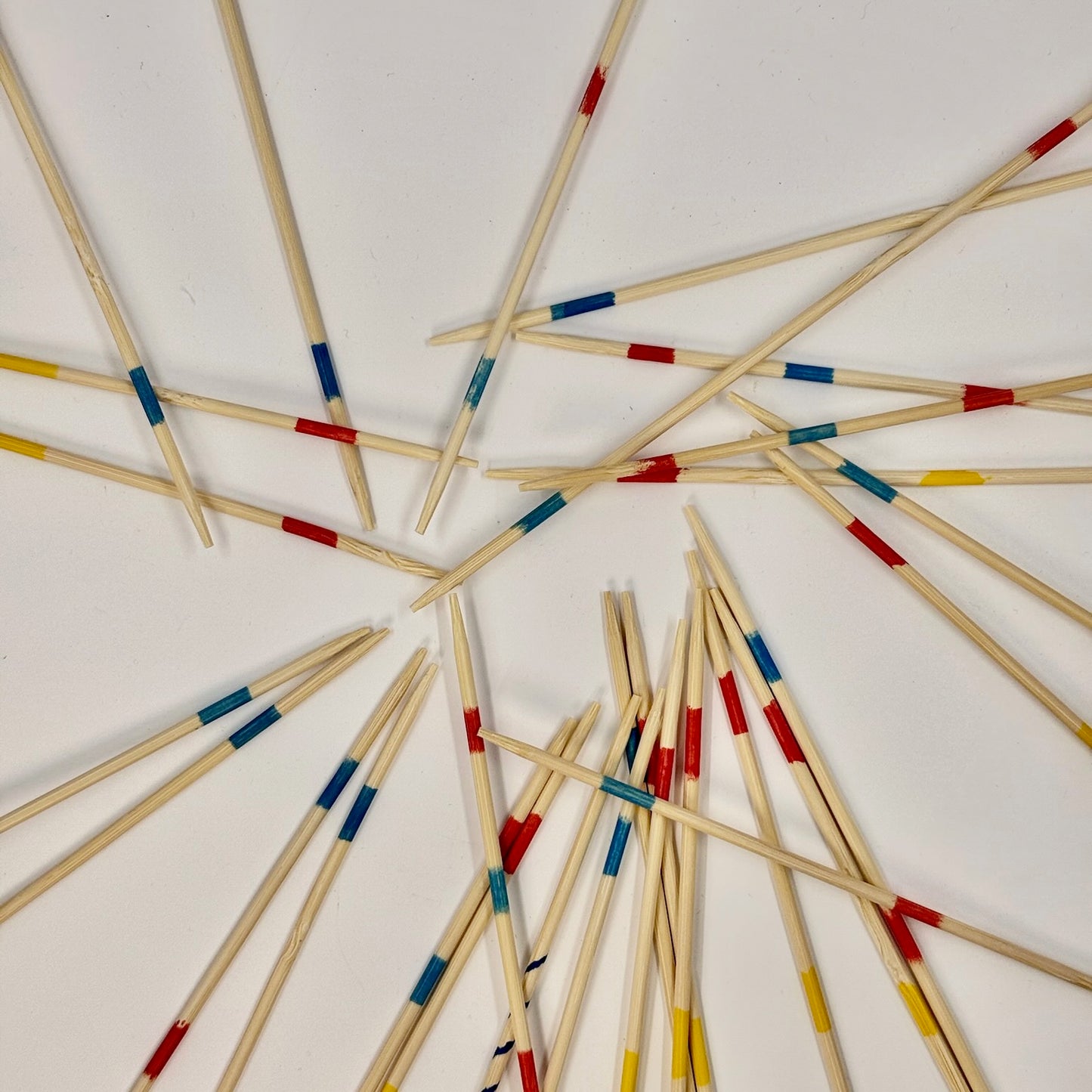 Wooden Pick Up Sticks game with colorful bands arranged in a circular pattern on a white background