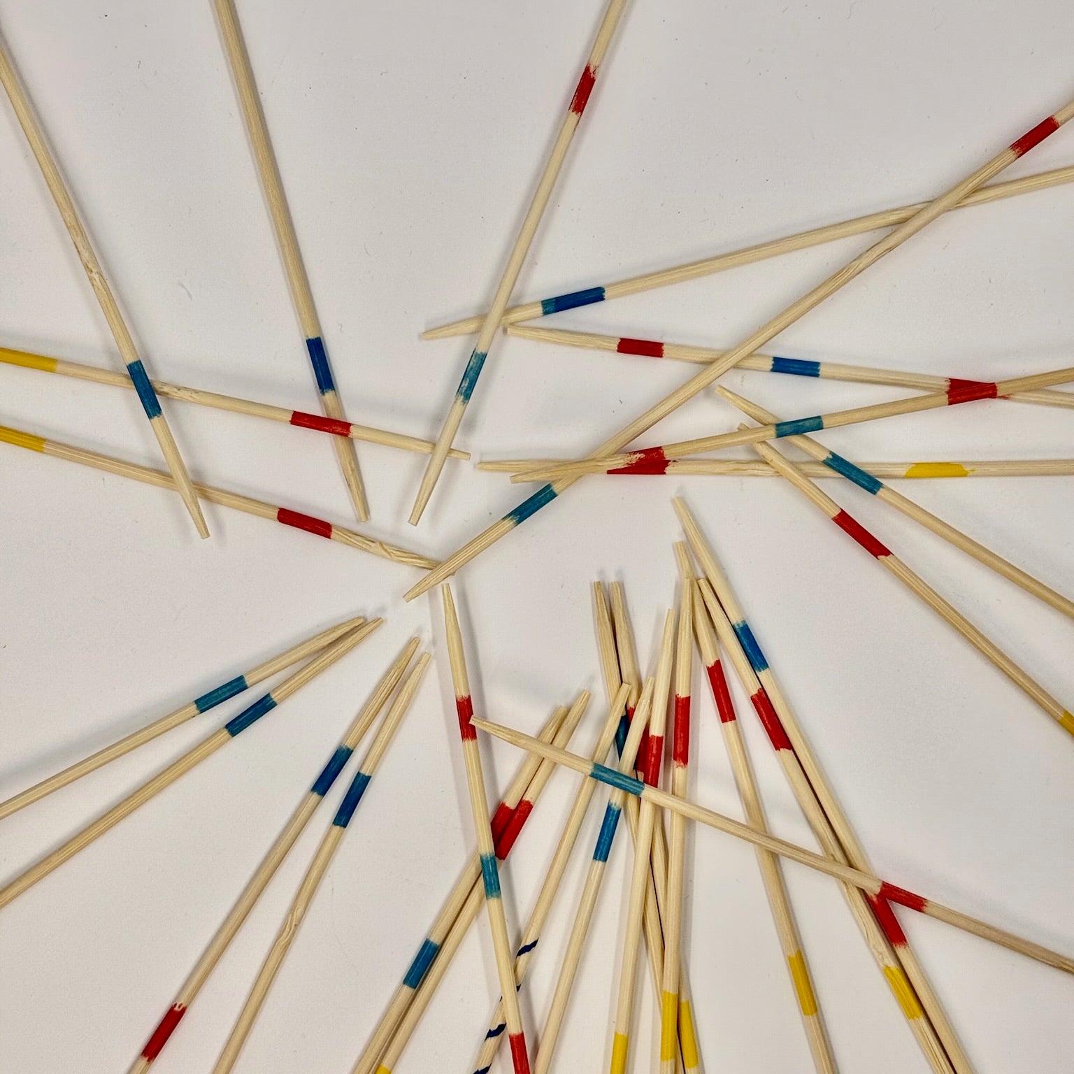 Wooden Pick Up Sticks game with colorful bands arranged in a circular pattern on a white background