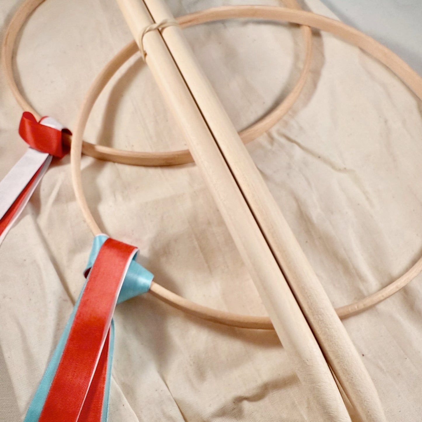 Beige Graces game consisting of hoops with red and blue ribbons on a beige fabric background