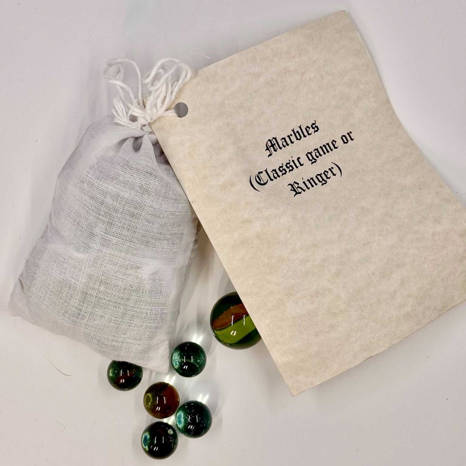 Marbles with a white drawstring bag and paper reading "Marbles (Classic Game or Ringer)" on a white background