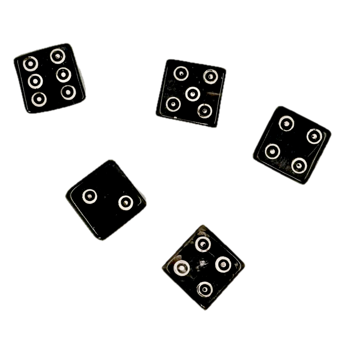 Five black horn dice with circular patterns on a white background