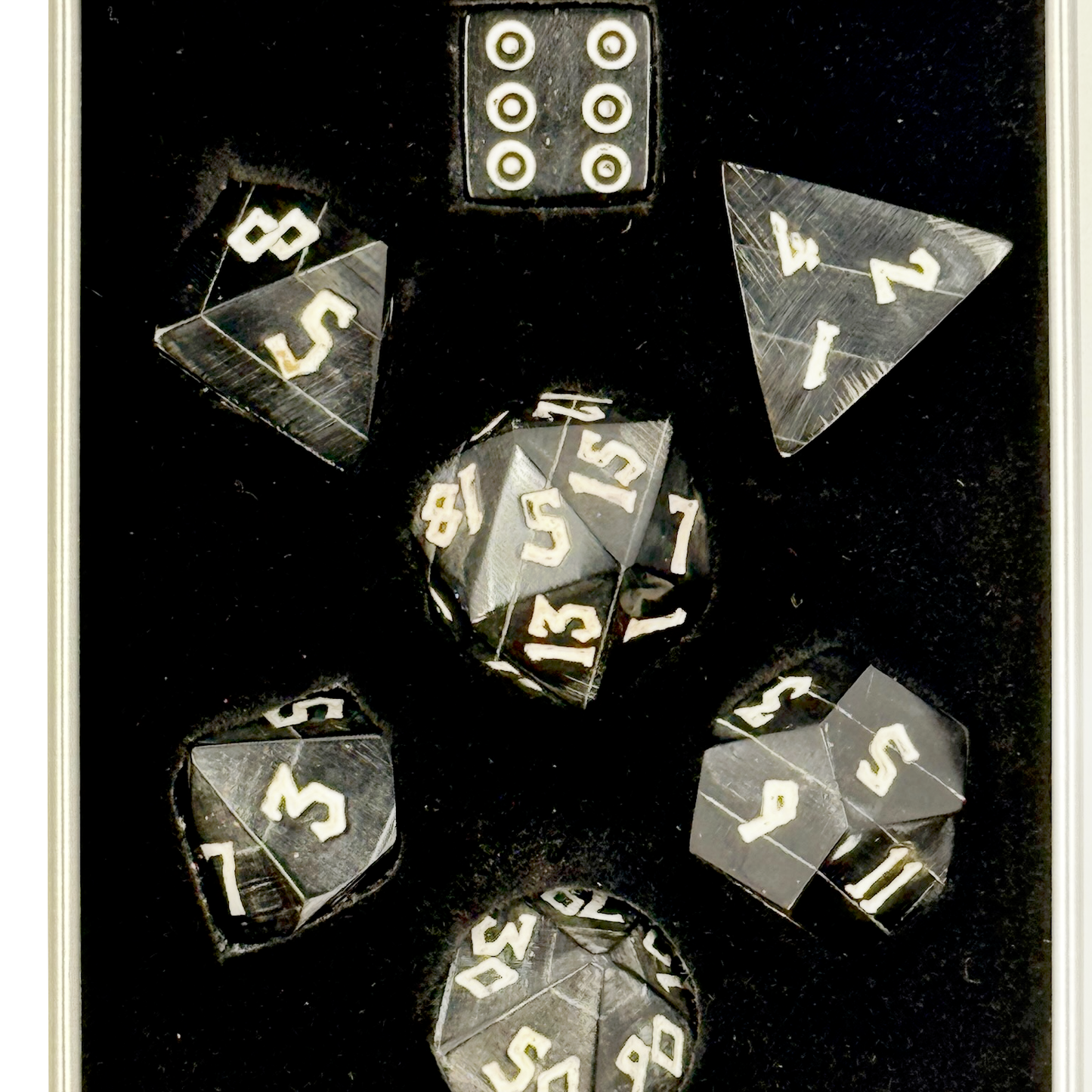 Set of polyhedral black horn dice with white numbers in a black box