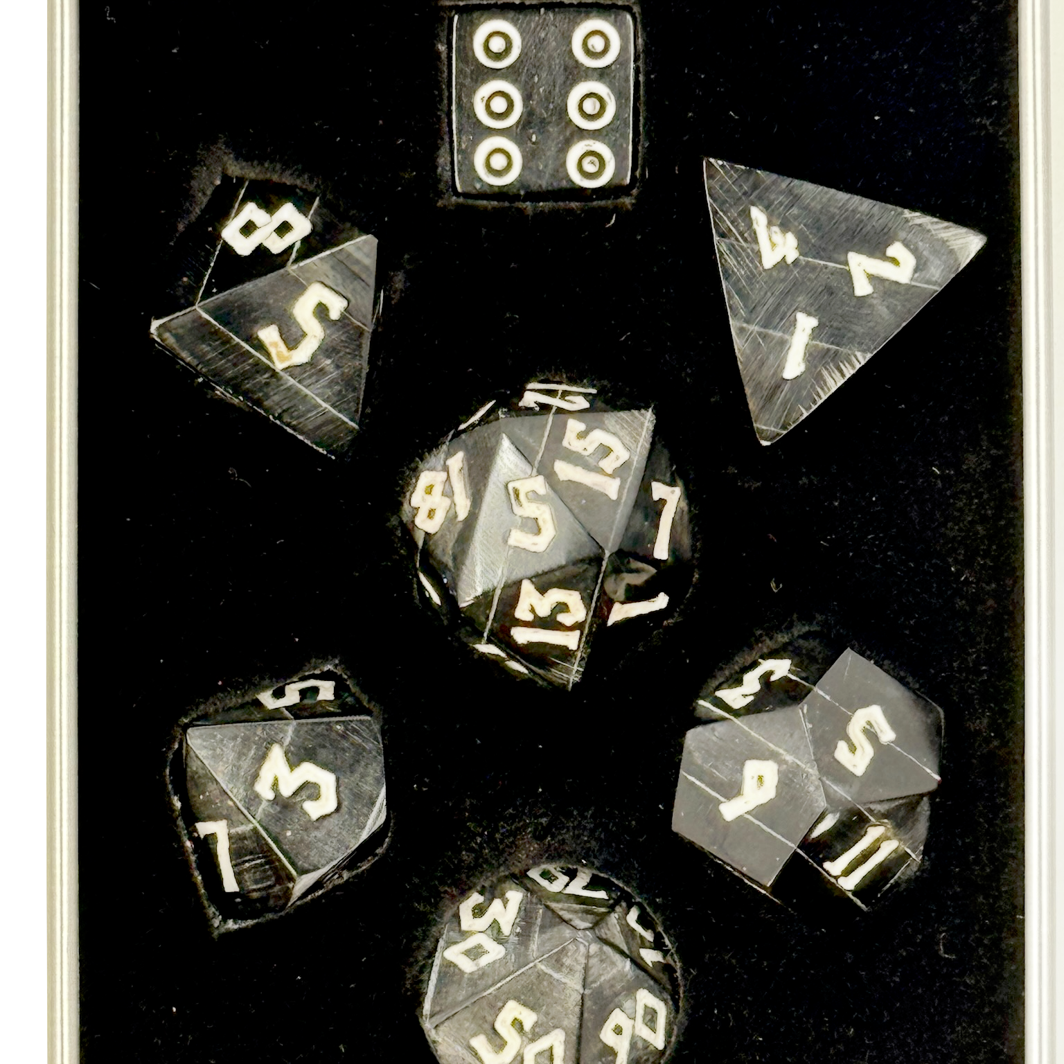 Set of polyhedral black horn dice with white numbers in a black box
