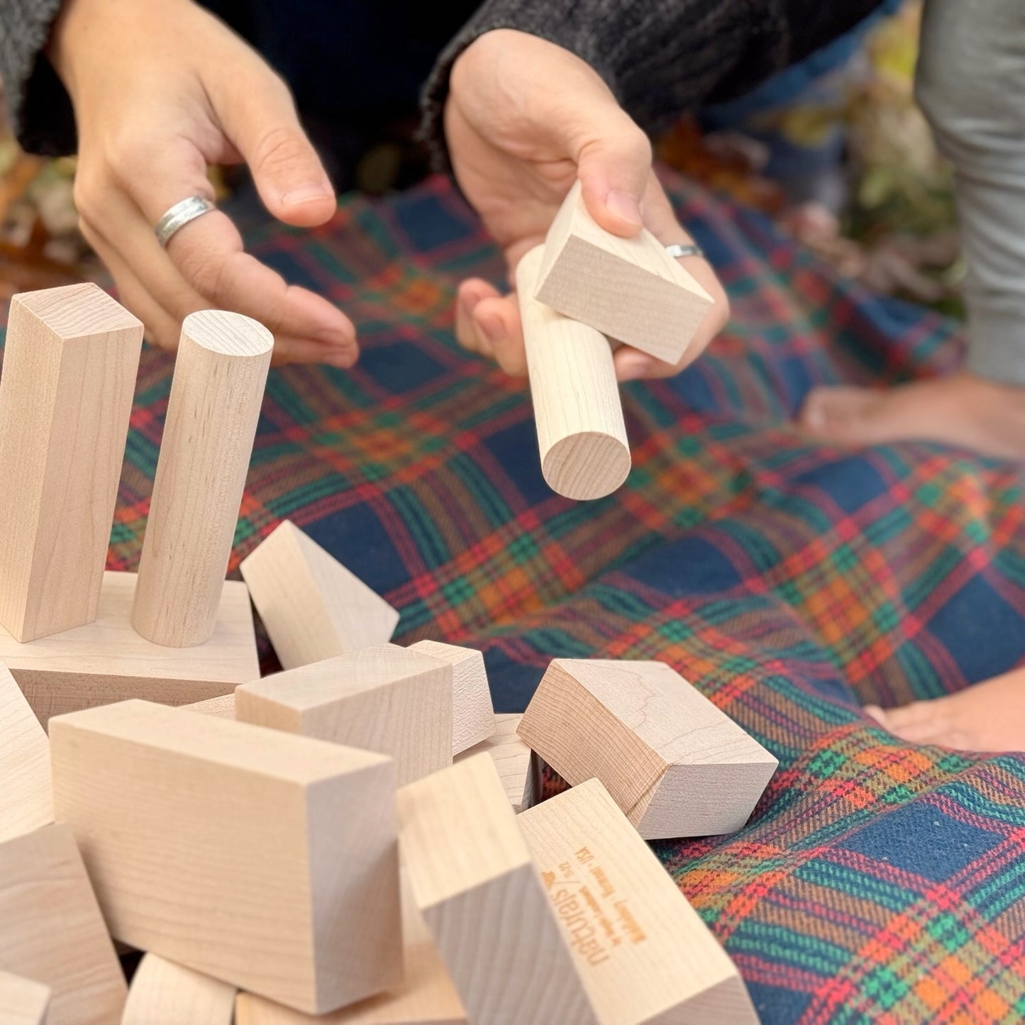 Hands playing with wooden blocks on a colorful fabric surface