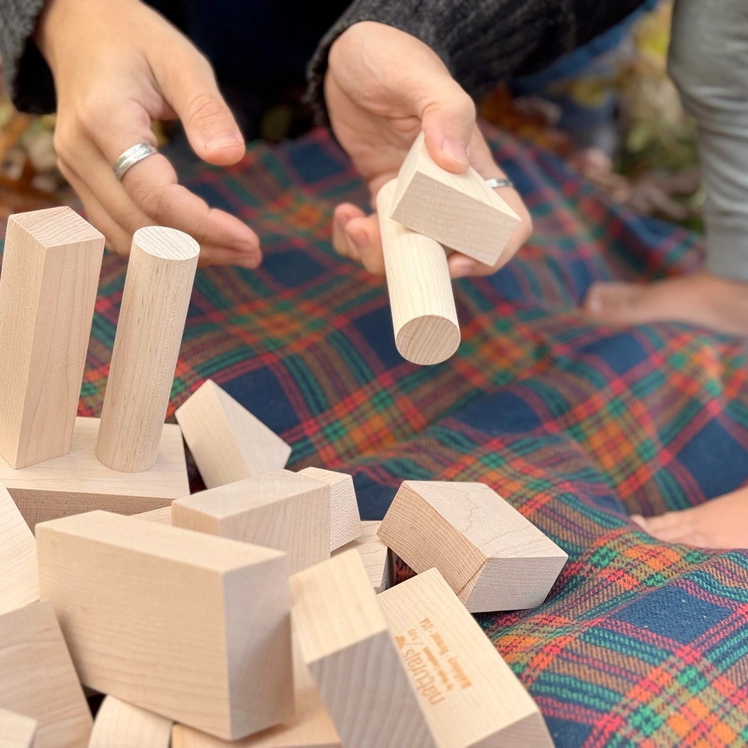 Hands playing with wooden blocks on a colorful fabric surface
