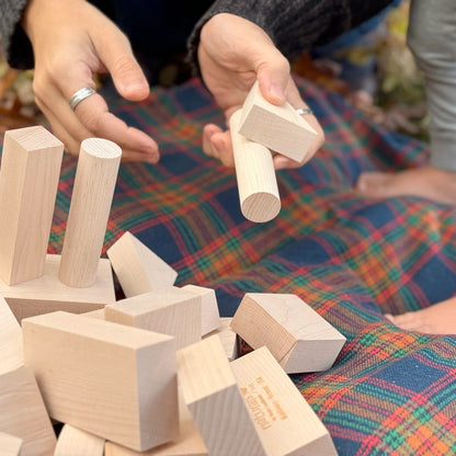 Hands playing with wooden blocks on a colorful fabric surface