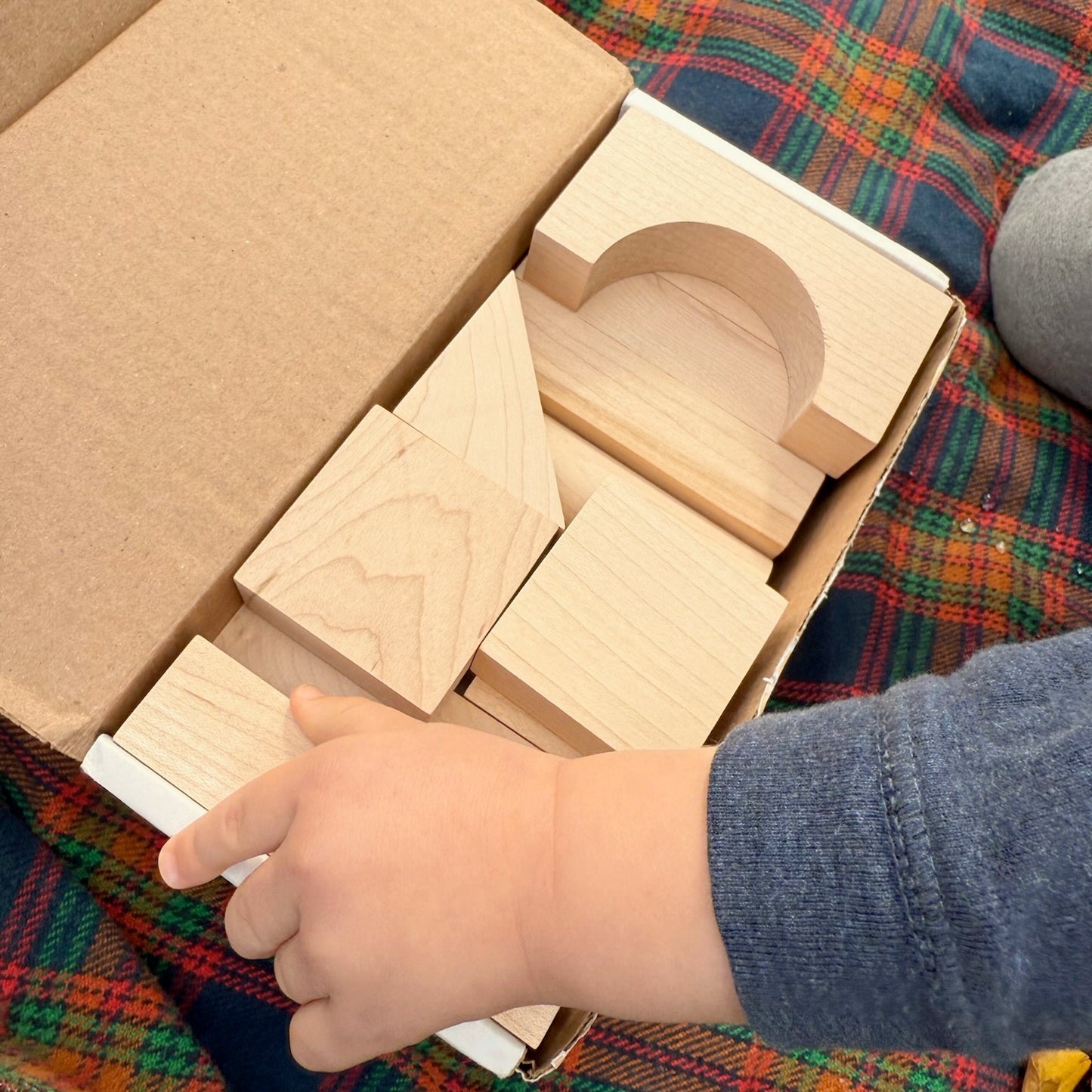 Child playing with wooden blocks on a plaid fabric surface