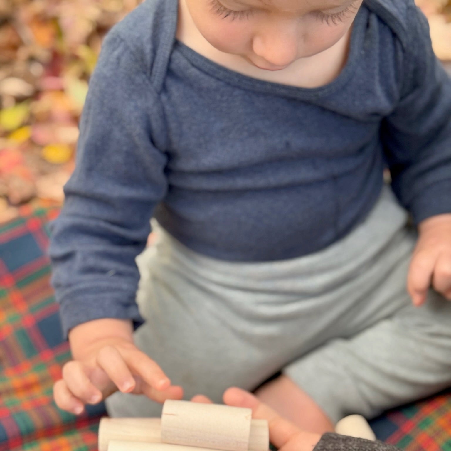 Child playing with wooden blocks on a plaid fabric surface