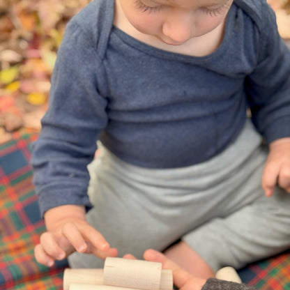 Child playing with wooden blocks on a plaid fabric surface