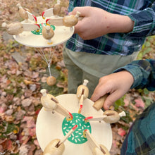 Two wooden Feeding Chickens toys being held by children outdoors with a blurred natural background.