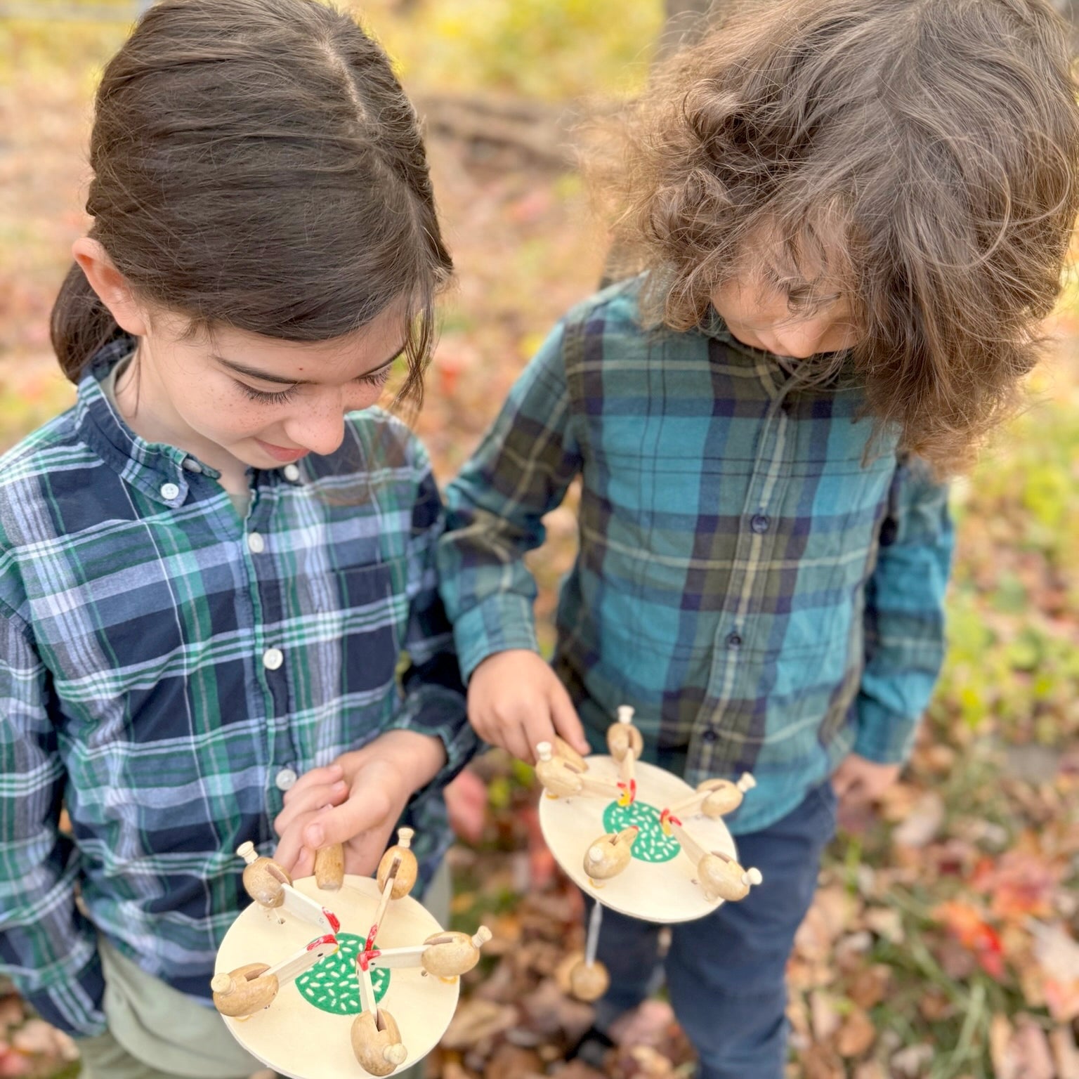Two children holding wooden Feeding Chickens toys on a natural background