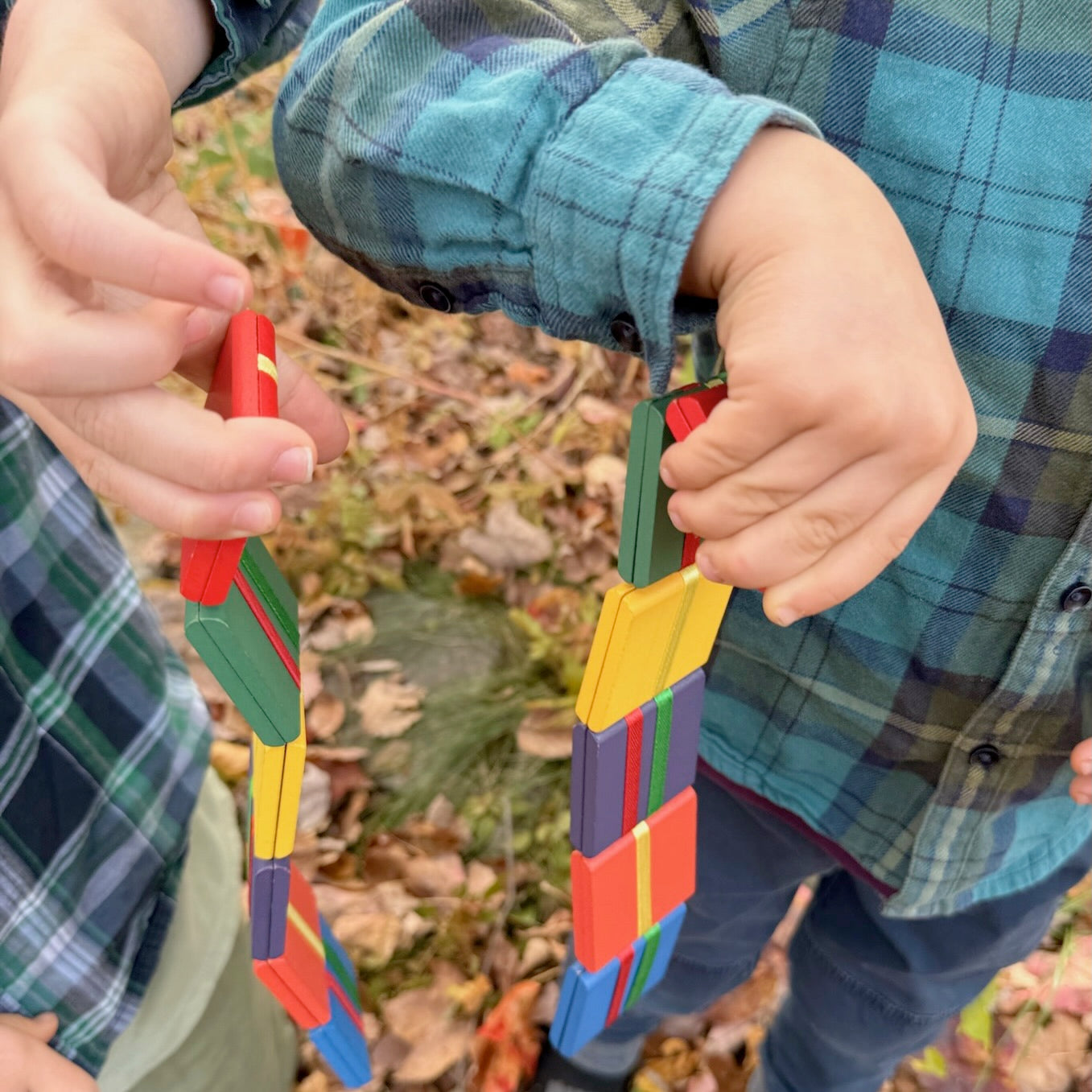 Two children holding colorful Jacob's Ladder toys outdoors with a natural background.