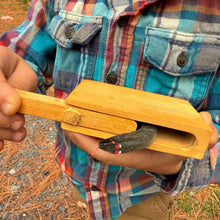 Child holding a Snake in the Box toy while wearing a plaid shirt outdoors