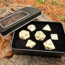 Set of bone dnd dice in a black metal case on a natural background