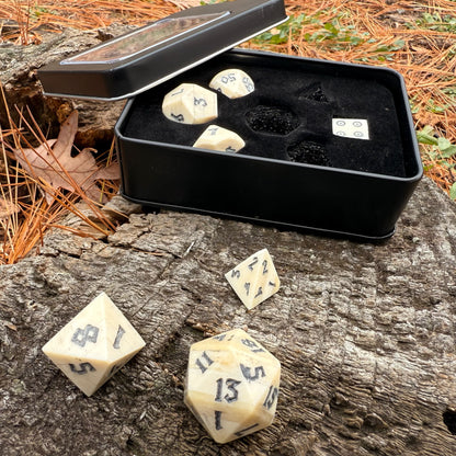 Set of polyhedral bone dice with a black storage box on a wooden surface