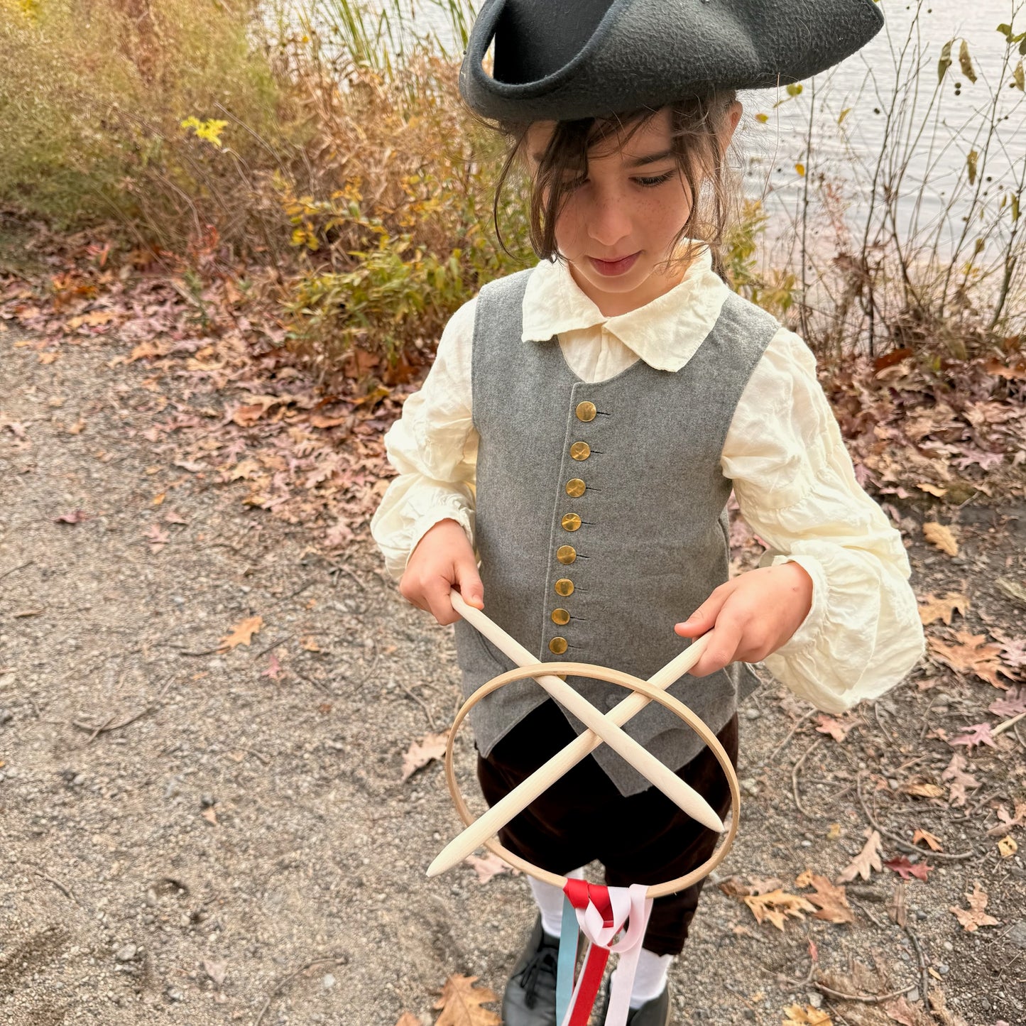 Child in colonial attire holding a Graces game outdoors