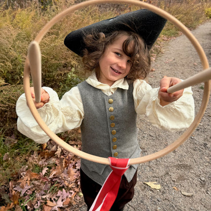Child in colonial attire holding a Graces game outdoors