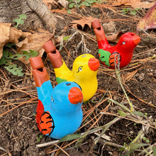 Colorful bird-shaped whistles on a natural background with leaves and twigs.