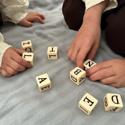 Children playing with letter blocks on a gray surface