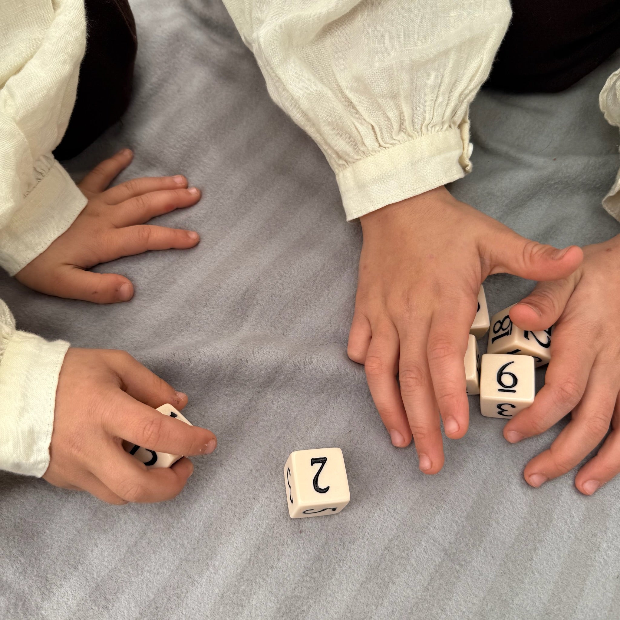 Children playing with dice on a gray surface