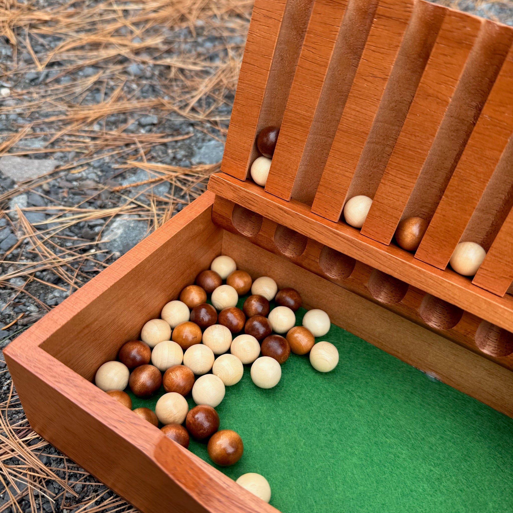 Wooden Captain's Mistress game with green interior containing wooden balls on a textured surface
