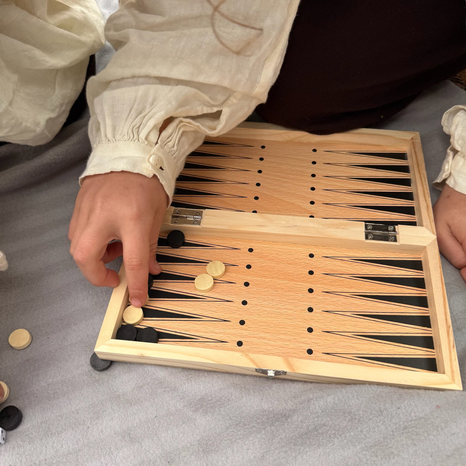 Child playing backgammon with wooden pieces 