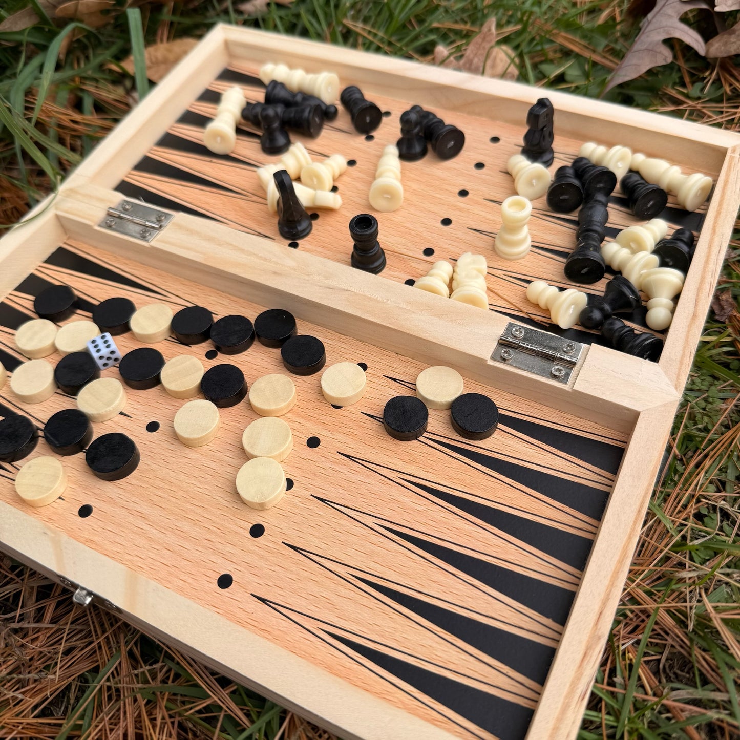 Wooden backgammon set with pieces on a grassy background
