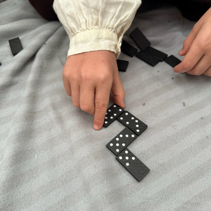Child playing with black dominoes on a gray surface