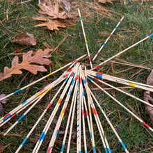 Colorful wooden Pick Up Sticks game on a grassy ground with fallen leaves