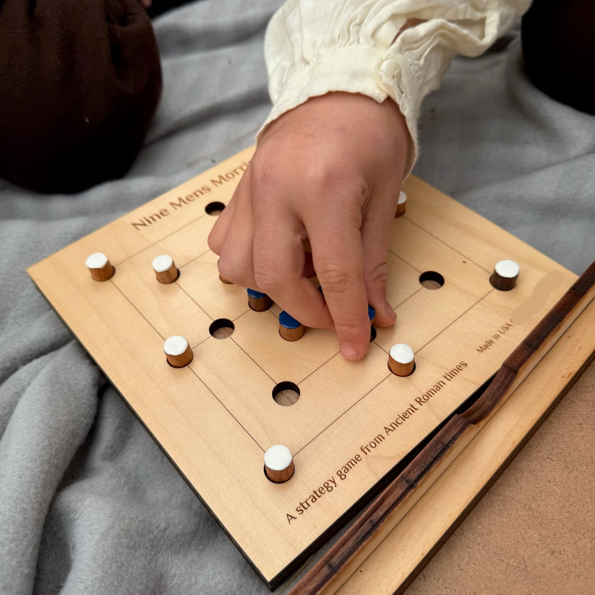 Child's hand playing a game of Nine Men's Morris