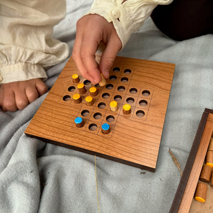 Child playing Solitaire with yellow and blue pieces on a natural background