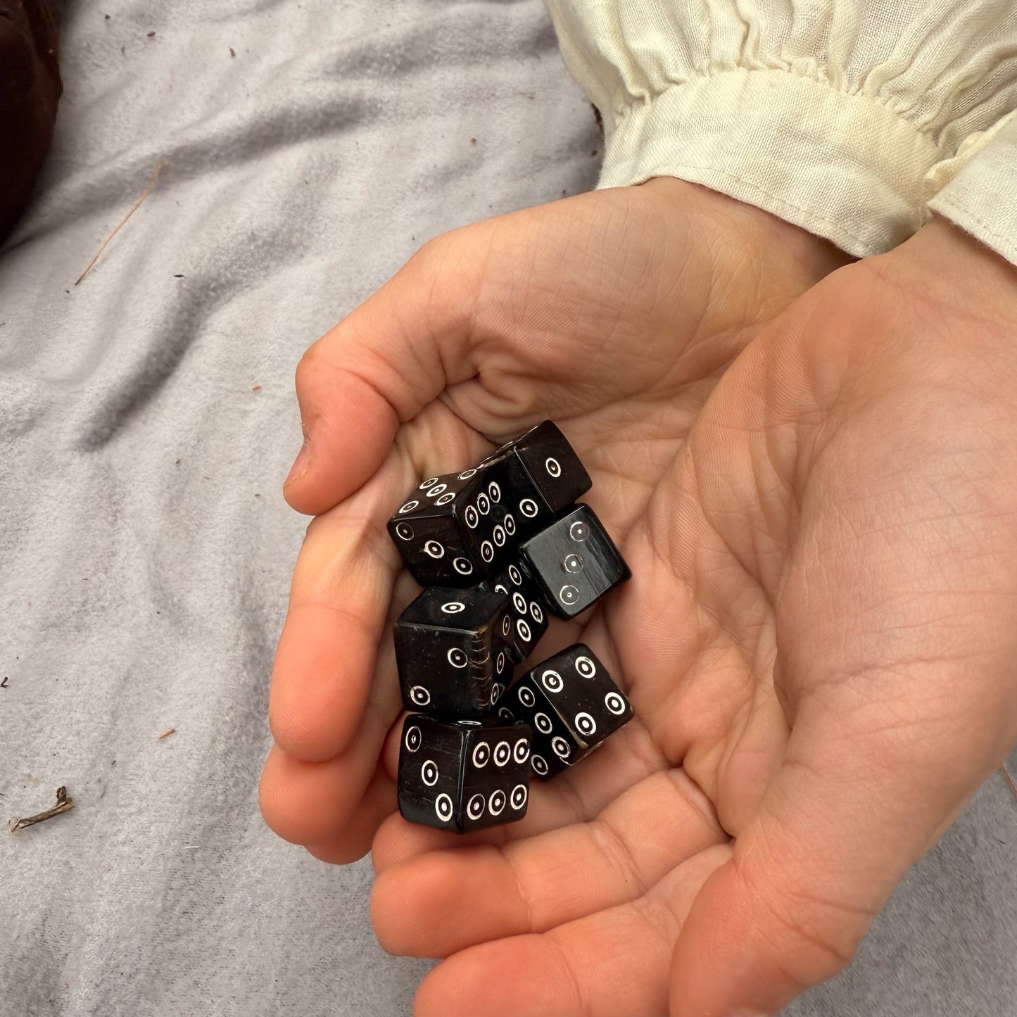 Hands holding black horn dice with white dots on a neutral background
