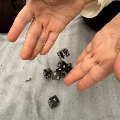 Two hands throwing black horn dice on a gray surface
