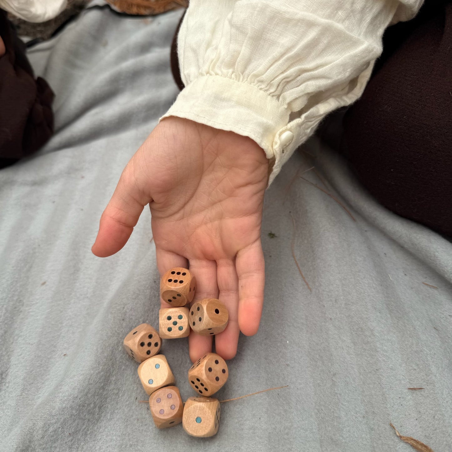 Hand holding wooden dice on a gray surface