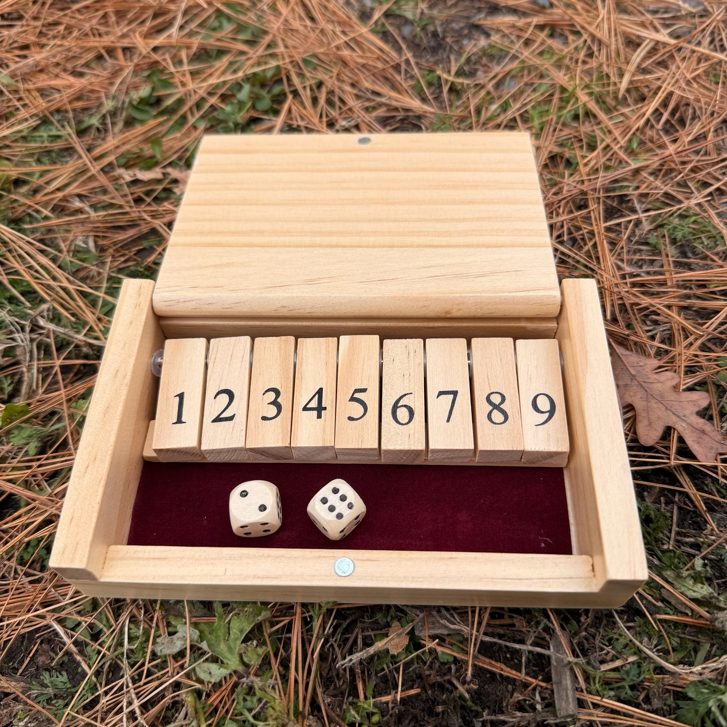 Miniature wooden Shut the Box game set with dice on a natural background