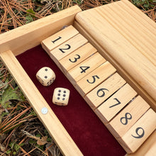Miniature wooden Shut the Box game with numbered blocks and dice on a natural background