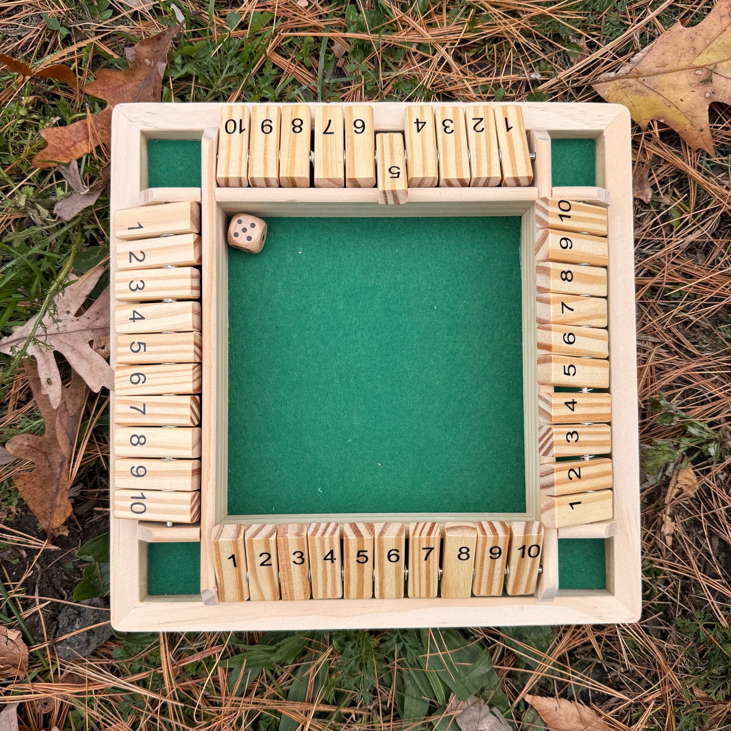 Wooden Shut the Box game on a grassy background