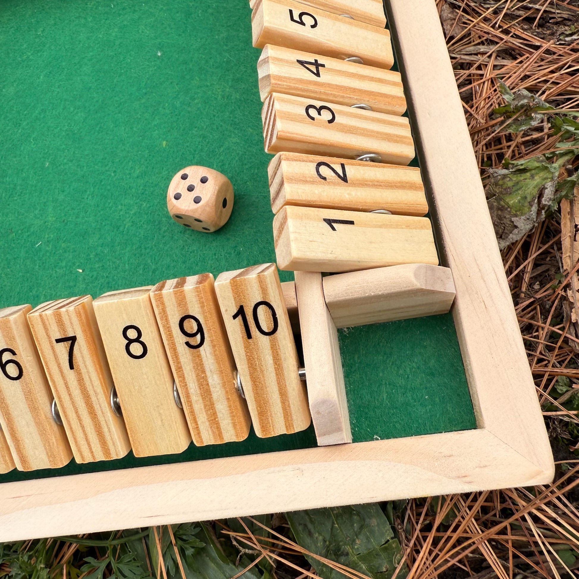 Wooden Shut the Box game on a bed of pine needles