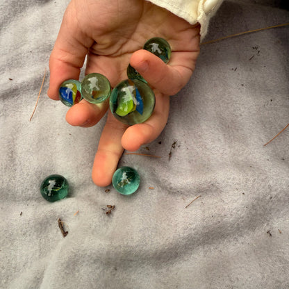 Hand holding colorful marbles on a grey surface