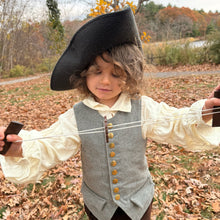 Child in colonial costume with a buzz saw toy outdoors in autumn setting